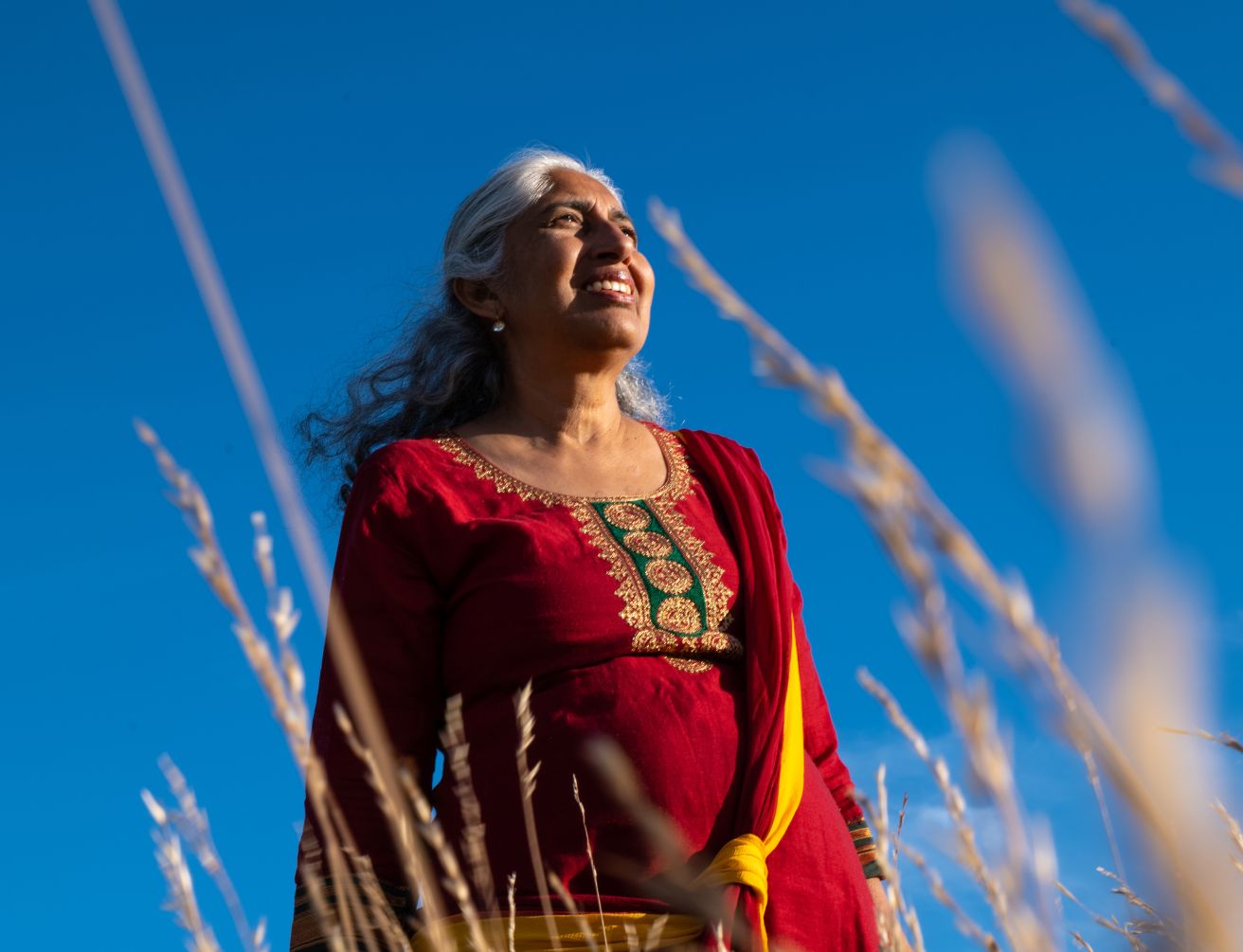 Yashi, souriante, au milieu des herbes hautes sous un ciel bleu