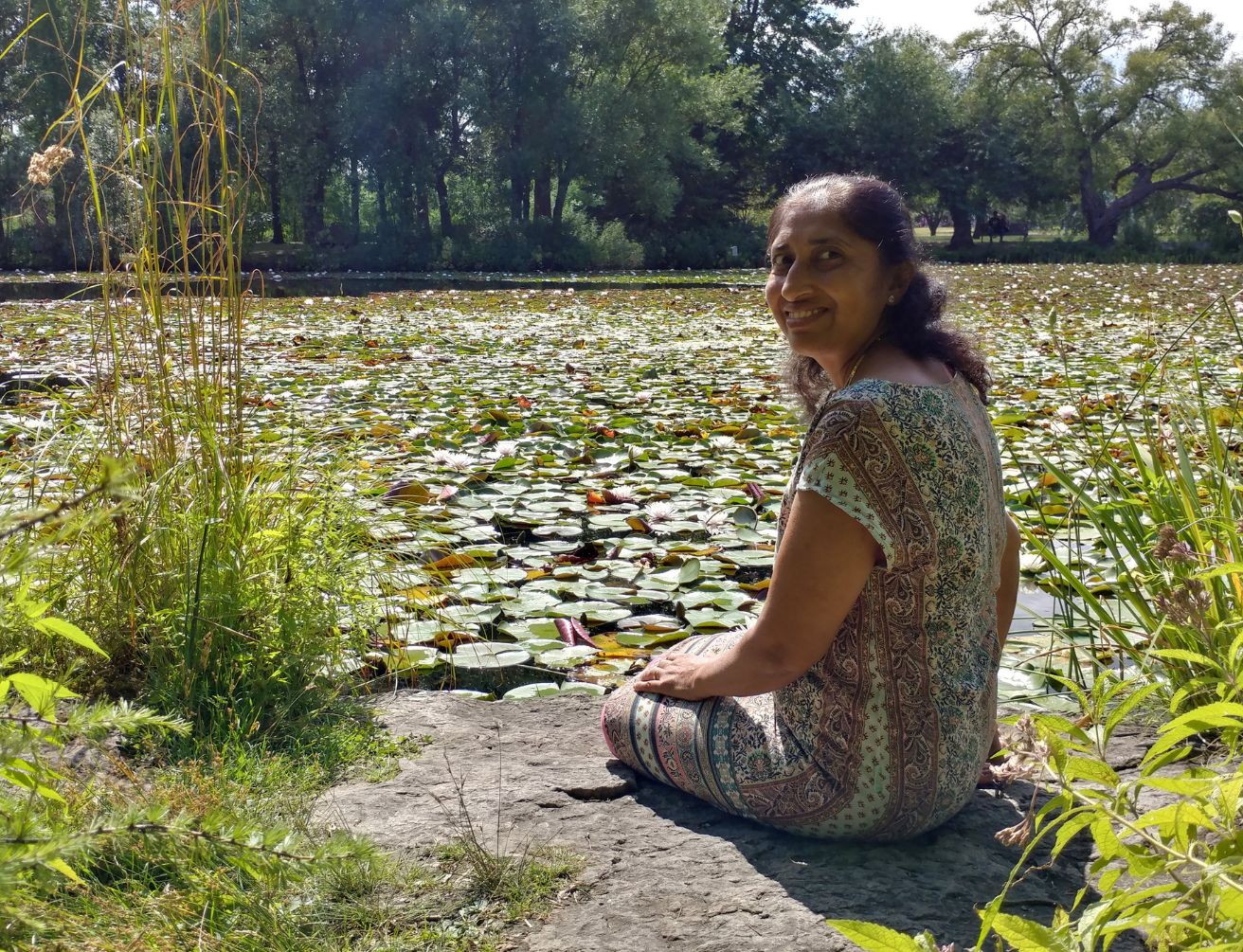 Yashi assise au bord d'un étang de nénuphars
